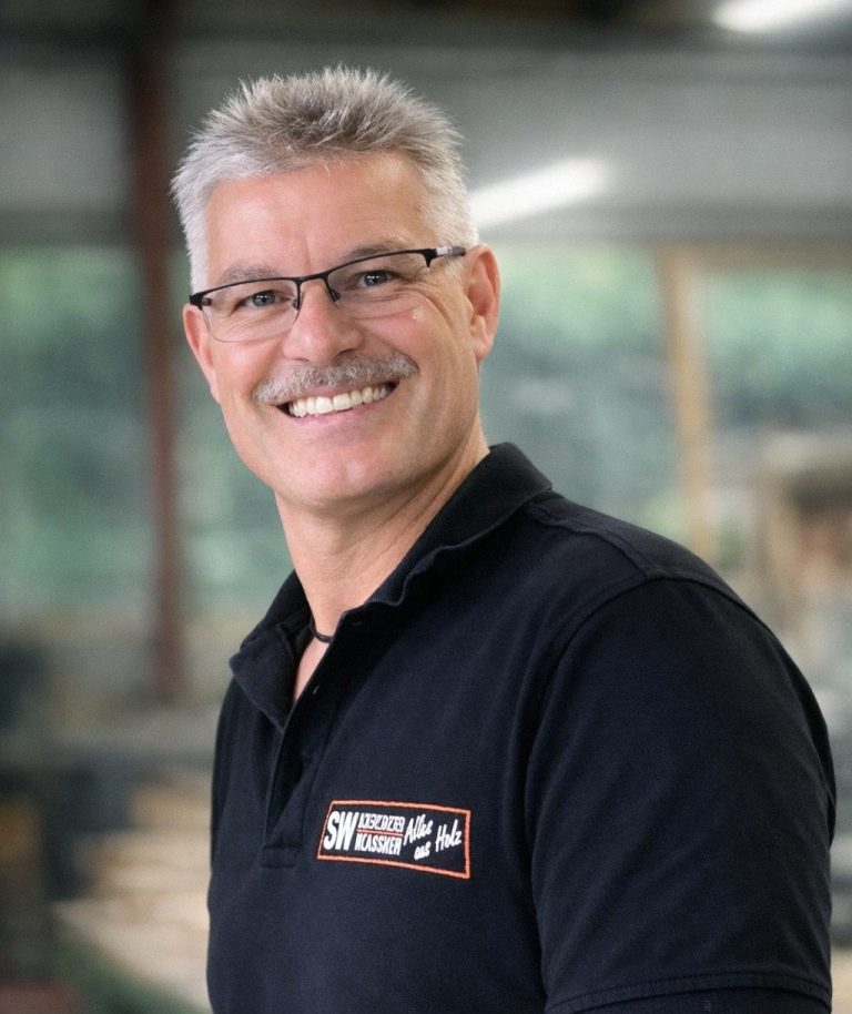 Ingo Wolfarth mit Brille, silbernes Haar und lächelndem Gesicht in einer hellen Umgebung.